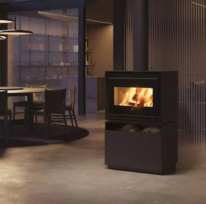 Primo piano di una stufa nera contenente della legna che emana calore in un ambiente intimo, circondato da luci soffuse.