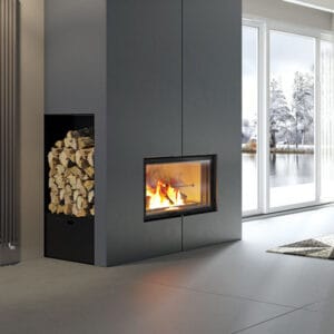 Immagine della stufa inserita all'interno di un grande contenitore grigio, in cui si nota un compartimento per il contenimento della legna. Della stufa si vede, in particolare, il fronte vetrato.